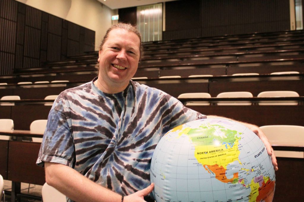 Easterbrook poses with blow-up globe in empty lecture hall