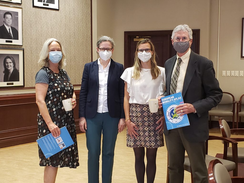 four people wearing face masks pose for a group photo