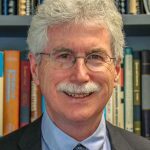 professor standing in front of colourful bookshelves