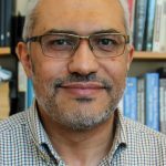 head shot of professor in front of bookshelves