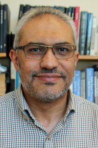 head shot of professor in front of bookshelves