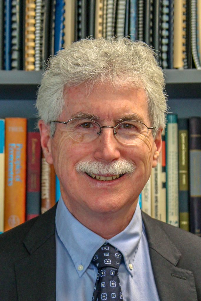 professor standing in front of colourful bookshelves